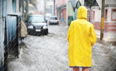 Person mit gelber Regenjacke auf einer Straße bei Regenwetter